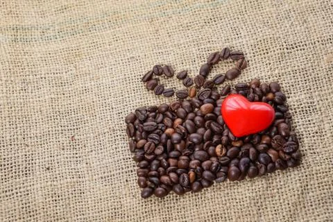 Present made of coffee beans on sackcloth with red heart Stock Photos