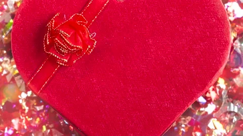 Present or gift box heart shaped with red bow and confetti on red background Stock Footage 148206897