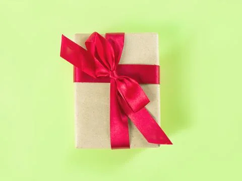 The present packed in the craft paper with red ribbon on the green background. Foto stock