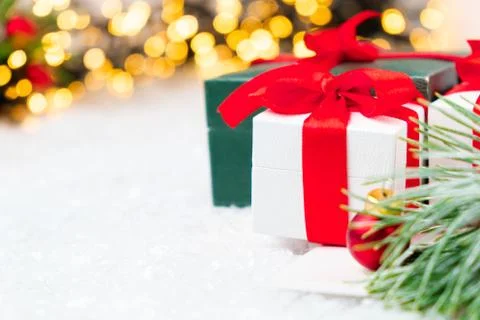 Present with red ribbon, pine or spruce branch with red balls on the snow on the Stock Photos