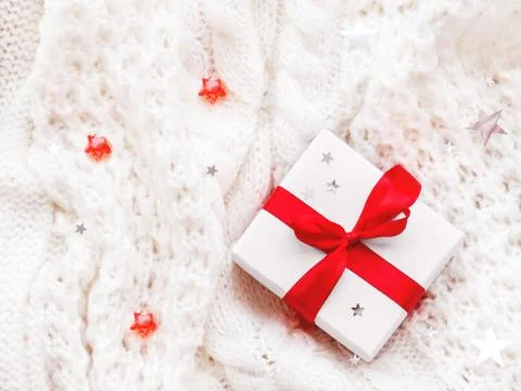 Present in white wrapping paper on white knitted backdrop. Holiday gift with  Stock Photos