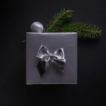 Present wrapped in silver paper with silver bow, bauble and spruce twigs Stock Photos