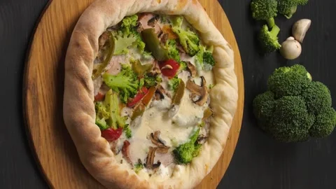 Presentation of pizza on a dark brown table with its ingredients. Video stock 211807751
