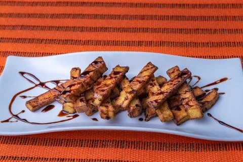Presentation in rectangular plate of aubergines cut into strips and fried Stock Photos