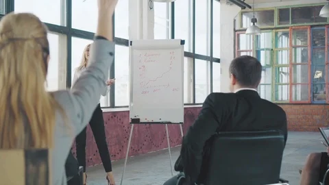 At the presentation, a young female manager gets up and discusses graphics with Stock Footage 107988948