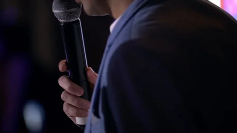 Presenter with microphone and folder performs on stage Stock Footage 104492437