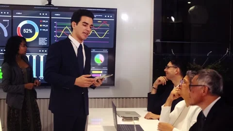 Presenter with tablet explains analytics dashboards to executives in boardroom Stock Footage 318578675