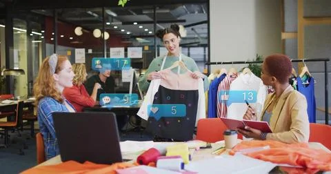 Presenting designer holding two-tone dress on hanger in open-plan workspace, Foto stock