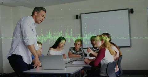 Presenting instructor in light shirt leaning over table, guiding students in Stock Photos