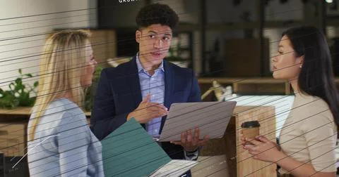 Presenting man in blazer holding open laptop, gesturing at office counter with Stock Photos