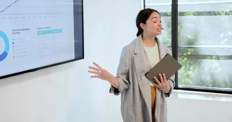 Presenting presenter in gray blazer speaking, gesturing in meeting room with Stock Photos