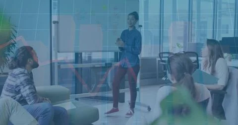 Presenting standing man wearing button-up talking to seated team in office, with Stock Photos