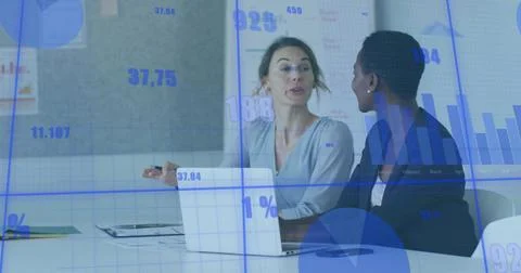 Presenting two colleagues in blazers analyzing data at meeting table, with Stock Photos