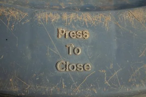 Press to close embossed text on a dirty gray plastic surface Stock Photos