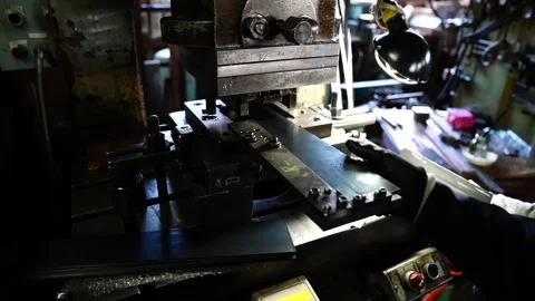Press machine stamping a tooth pattern into a long flat steel saw blade Stock Footage 345941791