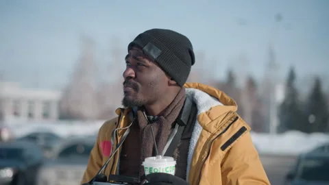 Press photographer sipping coffee while holding camera in snowy city Vídeo Stock 318636078