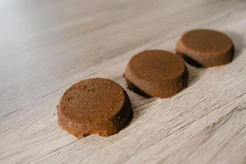 Pressed ground coffee tablets lie on the table Stock Photos