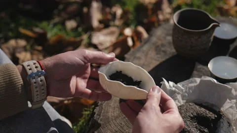 Pressed pu-erh tea in a ceramic bowl is demonstrated by a man. chinese tea Stock Footage 229858138