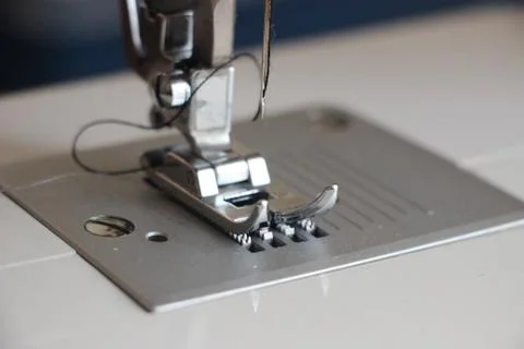 Presser foot of sewing machine threading the textile macro close up. Manufact Photos