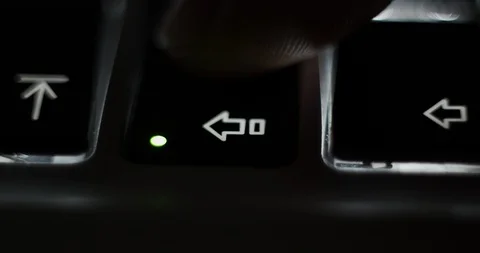 Pressing caps lock on backlit illuminated laptop computer keyboard at night Stock Footage 129306700