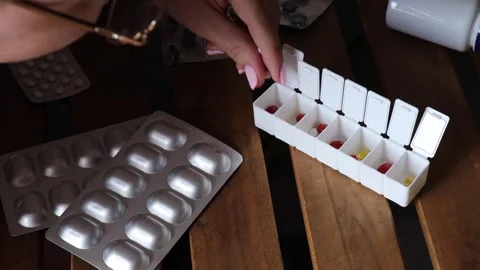 Pressing counterfeit pills and questionable supplements from blister into weekly Stock Footage 313794299