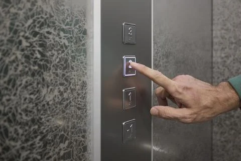 Pressing the elevator button in contemporary high rise buildings signifies Stock Photos