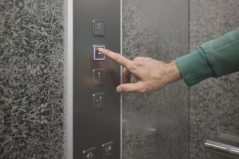 Pressing the elevator button in contemporary high rise buildings signifies Stock Photos