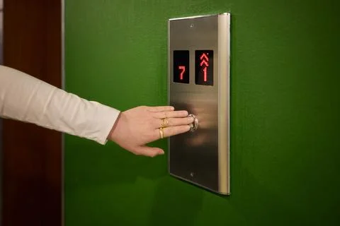 Pressing the elevator button in contemporary high rise buildings signifies Stock Photos