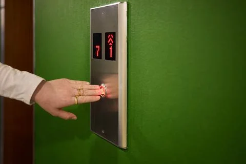 Pressing the elevator button in contemporary high rise buildings signifies Stock Photos