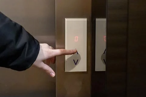 Pressing an elevator button with a hand, highlighting interaction with modern Fotos de archivo