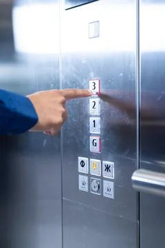 Pressing elevator button, person selecting third floor in modern office building Stockfoto's