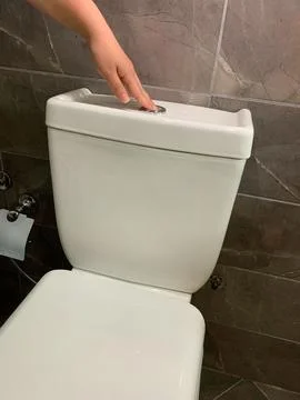 Pressing flush button on toilet to flush water Stock Photos