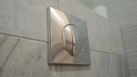 Pressing a large chrome button to flush the toilet. Modern water saving system Stock Footage 243161564