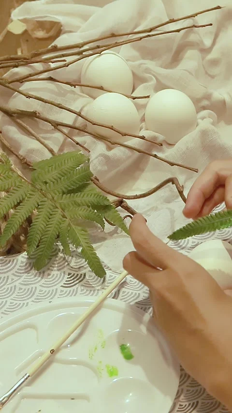 Pressing a painted fern leaf on an egg Stock Footage 307047355