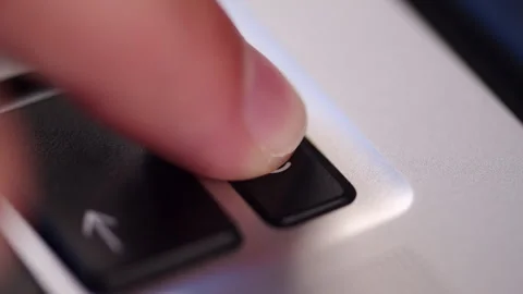 Pressing the power button icon on a silver laptop keyboard. Pushing the on .. Stock Footage 340958298