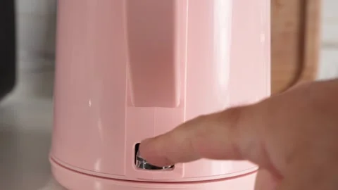 Pressing power button on pink kettle to switch it on in kitchen Stock Footage 343288979
