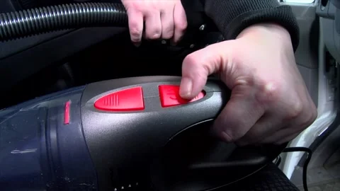 Pressing the red buttons on a black handheld vacuum cleaner for car Stock Footage 279176477