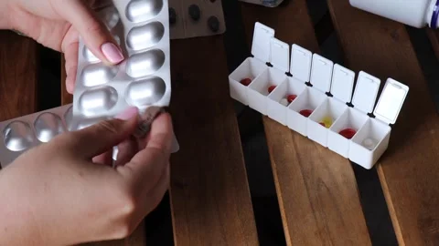 Pressing silver blister pack with probiotic capsules for gut health into weekly Stock Footage 313794325