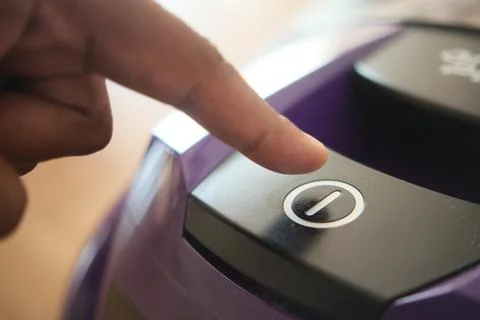 Pressing start button on vacuum cleaner. Stock Photos