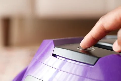 Pressing start button on vacuum cleaner. Stock Photos