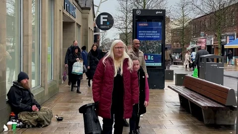 Preston UK, 03/02/2024; Rough sleeper seated on wet pavement in the city centre Stock Footage 266532796