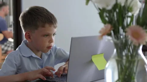 A preteen attentively completes a computer based assignment. Video stock 310780314