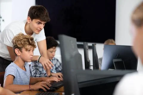 Preteen boy learning computer programs with teacher in training room 写真素材