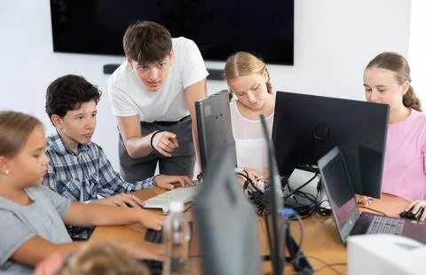 Preteen boy learning computer programs with teacher in training room Foto stock