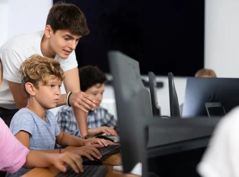 Preteen boy learning computer programs with teacher in training room Foto stock