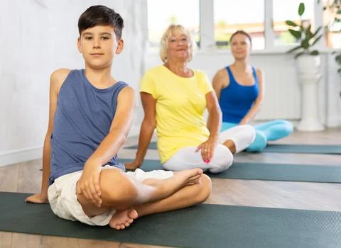 Preteen boy practicing revolved half lotus pose of yoga in light fitness room Stock Photos