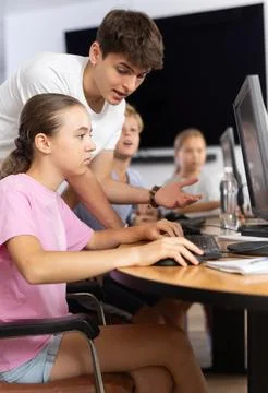 Preteen girl learning computer programs with teacher in training room Foto stock