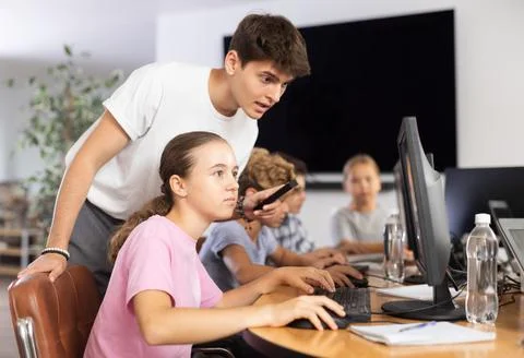 Preteen girl learning computer programs with teacher in training room Foto stock