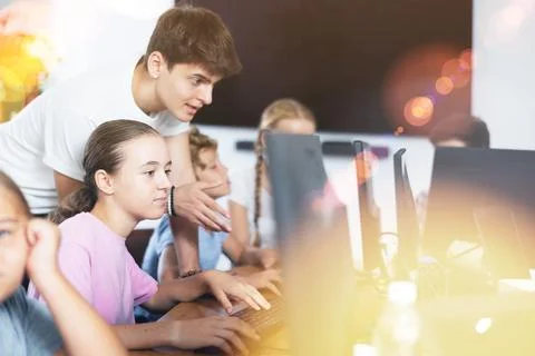 Preteen girl learning computer programs with teacher in training room Foto stock