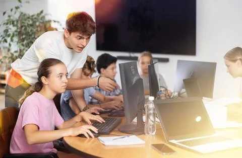 Preteen girl learning computer programs with teacher in training room Stock Photos
